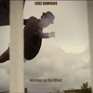 Waiting on the Wind cover: sepia‑toned image of Luke Hawkins tipping his hat beneath a cloudy sky